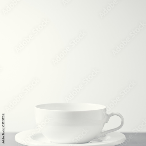 White porcelain tea cup shot against a creamy white background. With copy space.