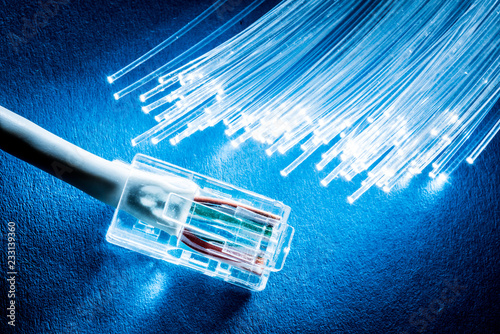 Network cable and optical fibers with lights on blue background.