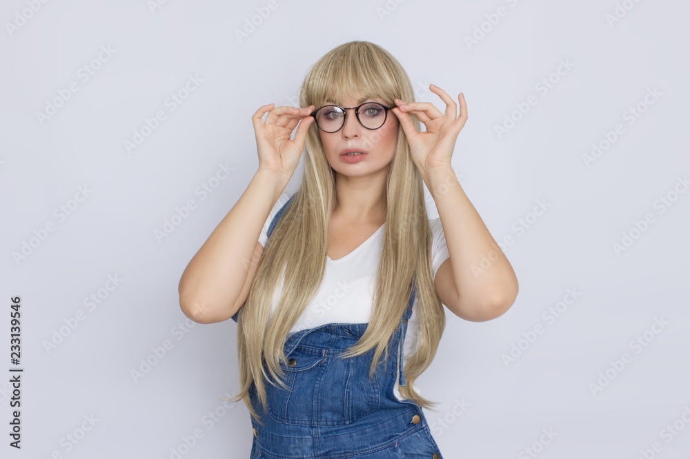 Young blond woman in jeans overalls and glasses Young blond woman in jeans overalls and glasses