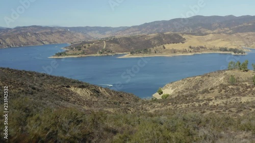 A blue lake in between hills with power boats and kayaks
