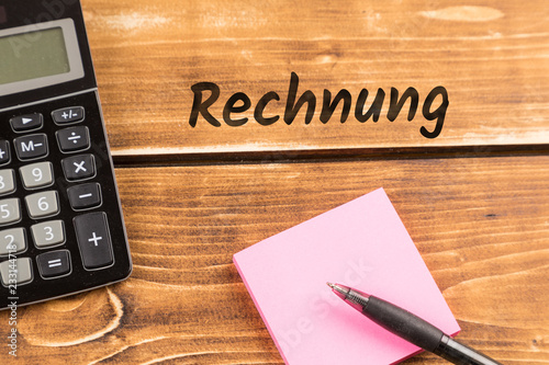 business desk with paper, pen and calculator with german text Rechnung, in english invoice