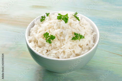 A photo of a bowl of cooked white long rice on a teal blue background with a place for text