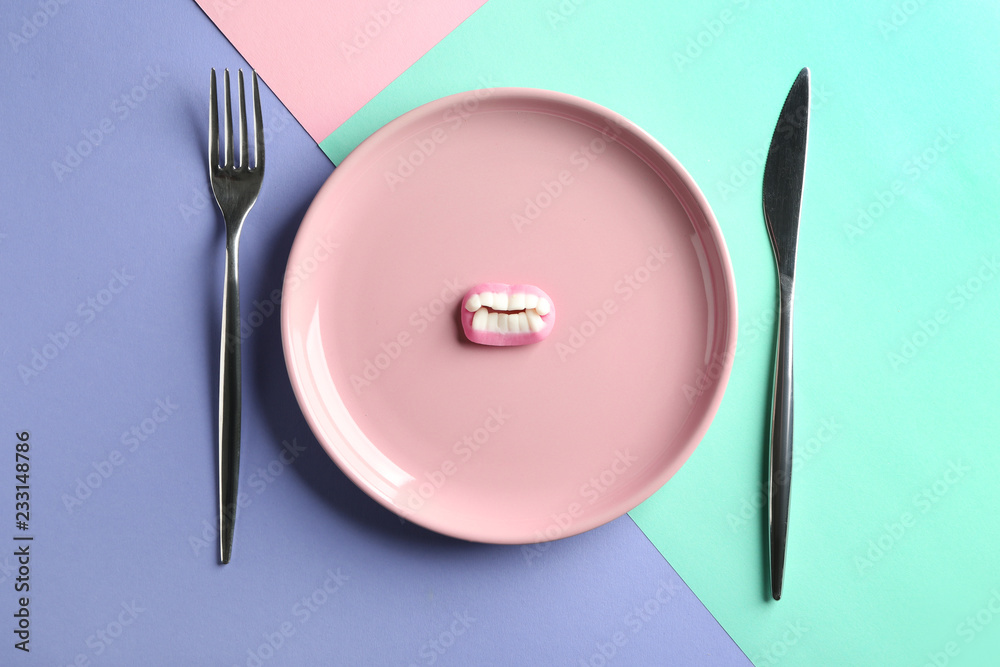 Plate with candy and cutlery on color background Plate with candy and cutlery on color background