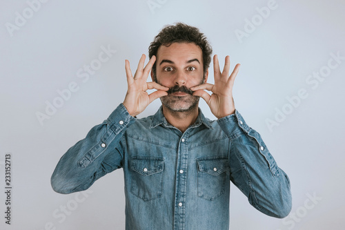 Fotografia Funny portrait of brown, smiling, handsome man touching his mustache
