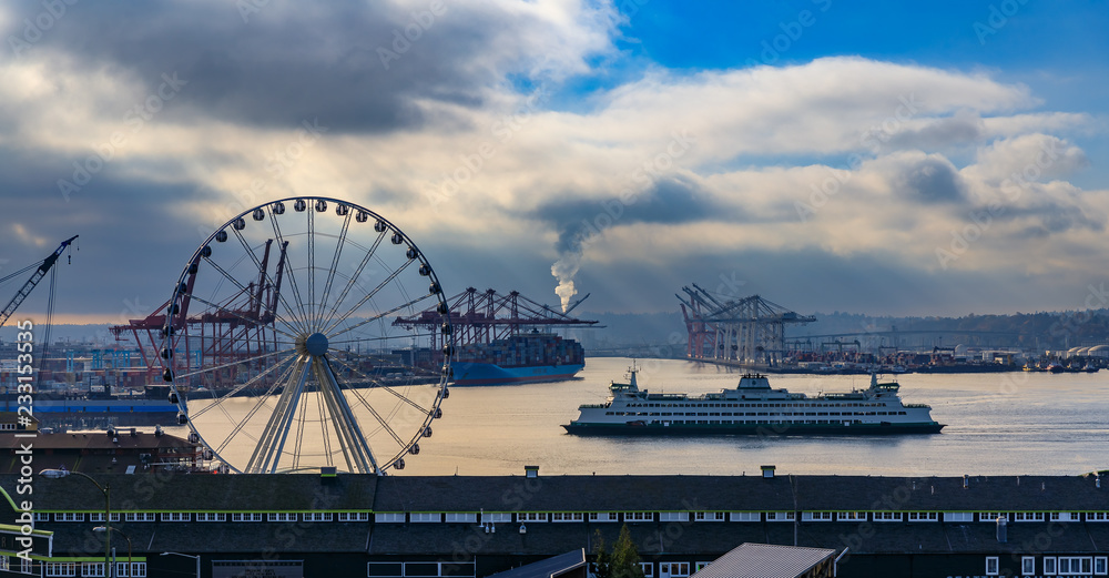 Seattle waterfront at sunset with Great Wheel and the Puget Sound with a ferry boat on a cloudy day