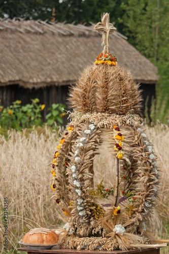 Tradycyjny wieniec dożynkowy upleciony ze suchych zbóż i kwiatów drewniana stodoła i słoneczniki