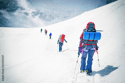 Group of climbers reaches the top of mountain peak. Climbing and mountaineering sport. Teamwork concept.
