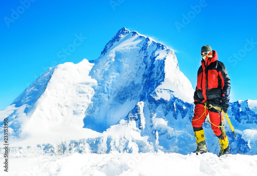 Climber reaches the top of mountain peak enjoying view of Himalayan mountains . Climbing and mountaineering sport. Teamwork concept.
