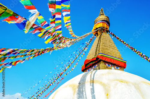 Bodhnath stupa in kathmandu with buddha eyes and prayer flags on clear Blue sky background.