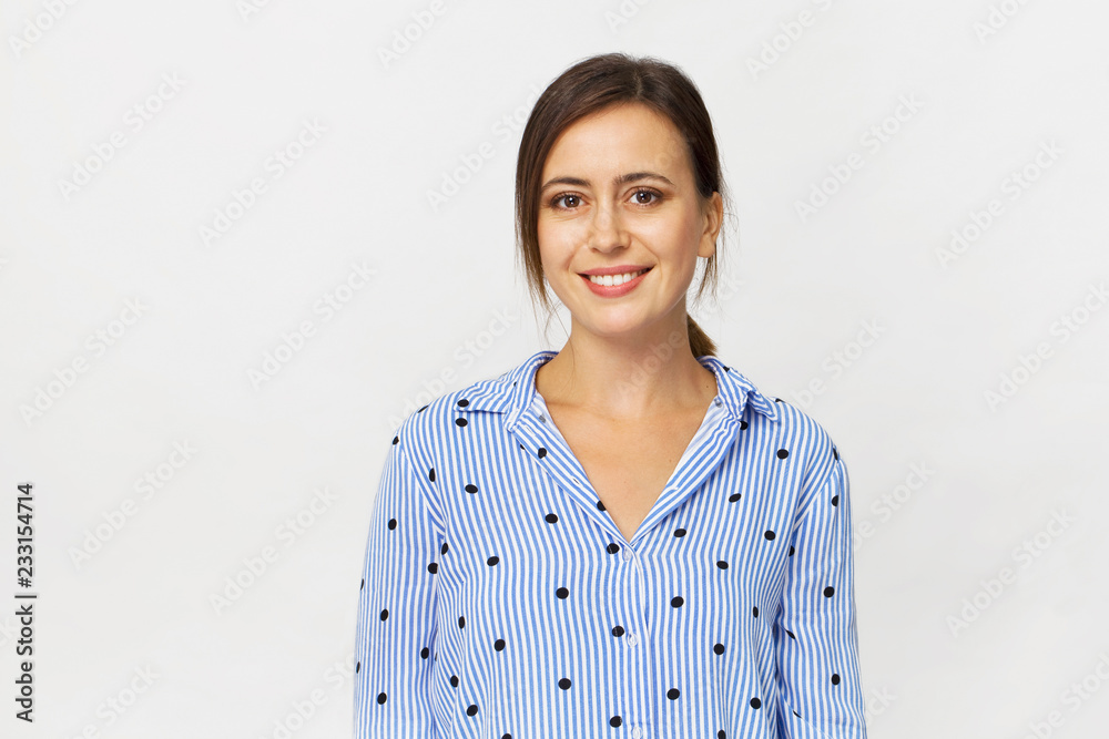 Happy young brunette woman wearing blue shirt smiling portrait against white background Happy young brunette woman wearing blue shirt smiling portrait against white background