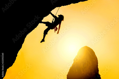 Silhouette of man climbing at sunset. The rock climber during rock conquest. Climbing sport concept.
