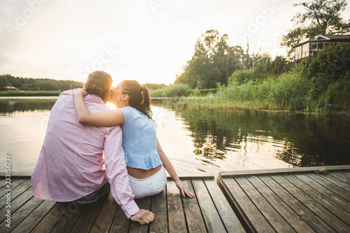 Woman kissing boyfriend on dock during sunset photo