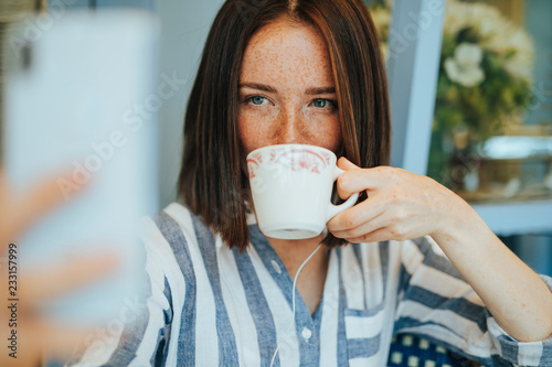 Woman taking a selfie while drinking a coffee