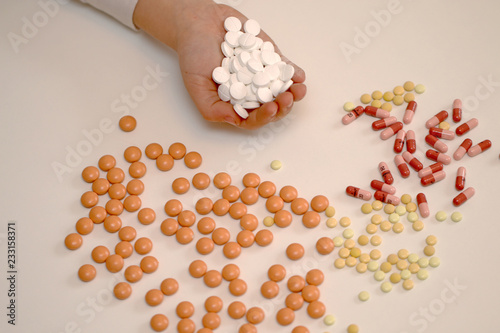 Medication on a white background and in the hand, a pin and a pill