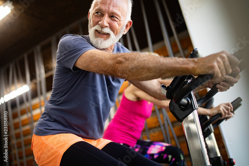 Happy senior people doing indoor biking in a fitness club © NDABCREATIVITY