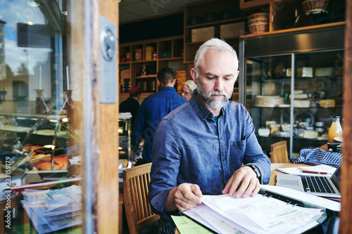 sales clerk reading documents while sitting at table in store