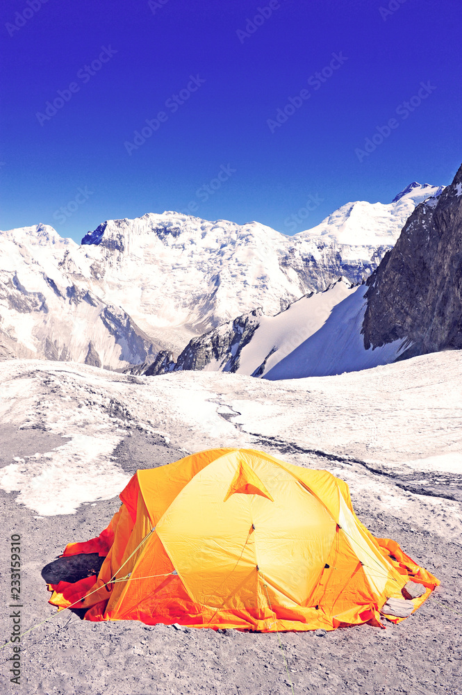 The bright orange camping tent in hight mountains. Climbing and mountaineering sport. Nepal mountains.