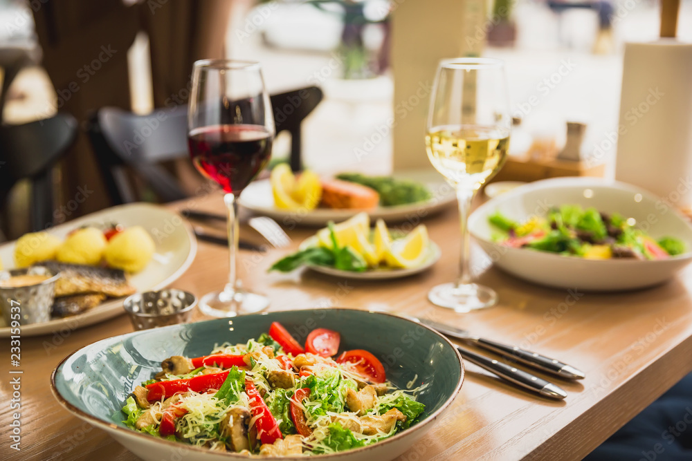 Festive dinner with tasty salads, fish dishes and glass of wine. Healthy food in cafe
