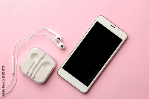 White smartphone and headphones on a bright pink background. view from above