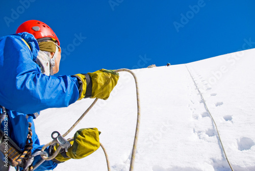 Climber with backpacks reaches the summit of mountain peak. Success, freedom and happiness, achievement in mountains. Active sport concept.