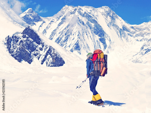 Hiker with backpack crossing crevasses filed during ascend the summit of mountain peak in Himalaya. Success, freedom and happiness, achievement in mountains. Active sport concept.