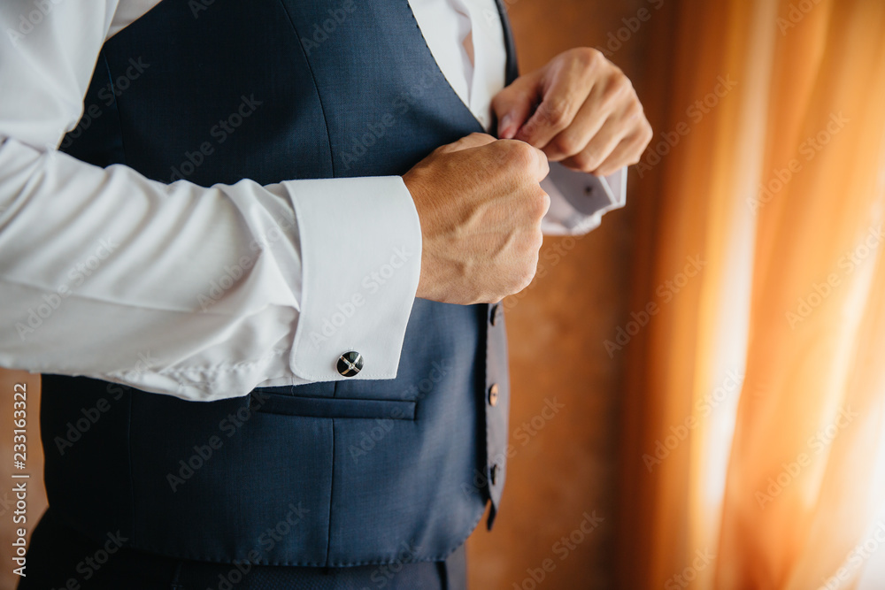 Close-up business stylish man buttoning his jacket, standing in a stylish office with designer repair.