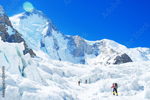 Group of climbers reaches the summit of mountain peak. Three climber on the glacier. Success, freedom and happiness, achievement in mountains. Climbing sport concept.