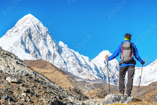 Hiker with backpacks reaches the summit of mountain peak. Success, freedom and happiness, achievement in mountains. Active sport concept.