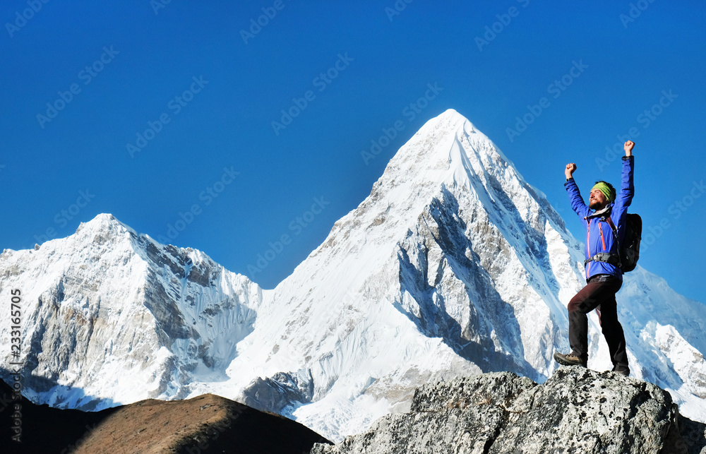 Hiker with backpacks reaches the summit of mountain peak. Success freedom and happiness achievement in mountains. Active sport concept.