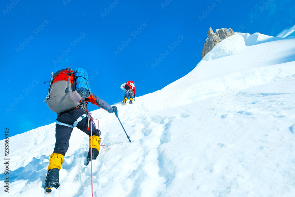 Group of climbers with backpacks reaches the summit of mountain peak Everest. Success, freedom and happiness, achievement in mountains. Active sport concept.