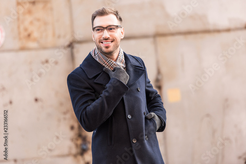 handsome man standing near rustic metal wall