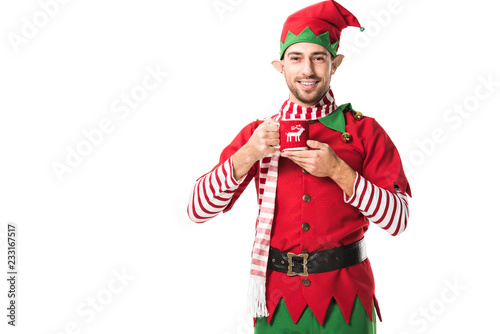 smiling man in christmas elf costume holding cup of tea and looking at camera isolated on white photo