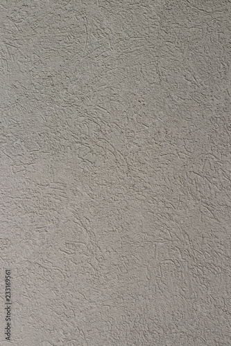 The rough wall covered with plaster of light-gray color