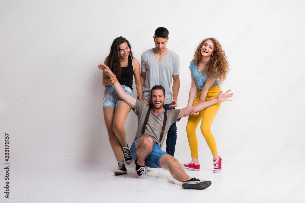 Fototapeta premium Portrait of joyful young group of friends standing in a studio.