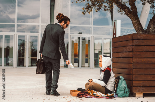Cuadro en lienzo Generous businessman helping a homeless on the street