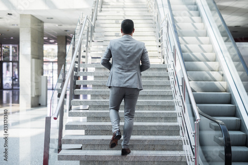 фотографія Ambitious businessman going up staircase. Back turned.