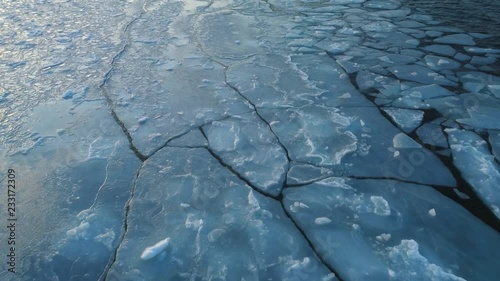 Frozen winter sea melting and ice floes drifting with waves aerial shot