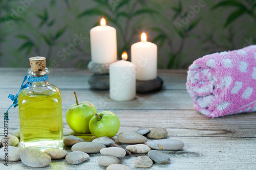 bottle of apple oil massage  river pebbles and two small green apples
