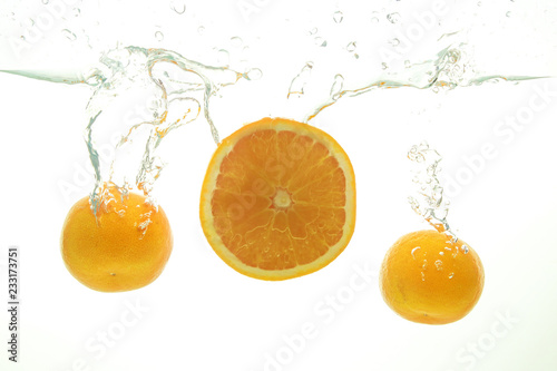 Two mandarine and orange slice splash of water on white