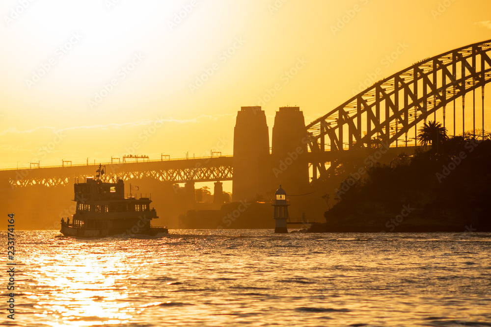 Obraz premium Sunset on Sydney Harbour with a famous Sydney Ferry and the Harbour Bridge as a backdrop.