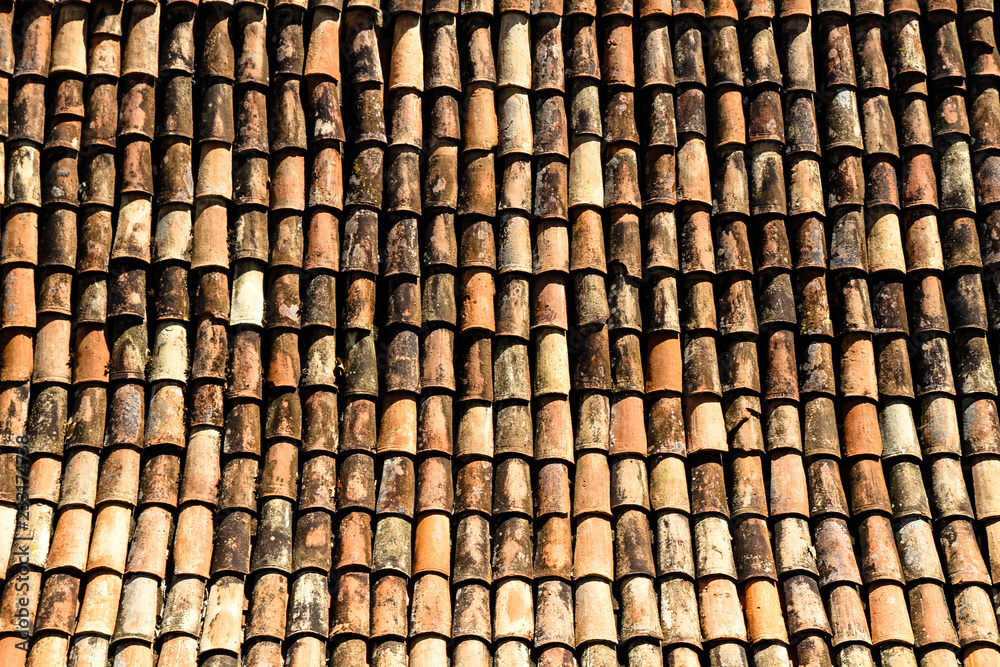 Detail from traditional old house roof with old brown ceramic tiles, damaged and worn out by exposure to the elements.