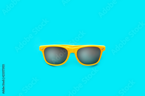 Yellow sunglasses in intense cyan blue large background. Minimal image concept for ready for summer, sun protection, hot days and tropical travel vacation.