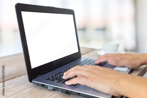 hand using laptop with blank white screen on wooden table in cafe