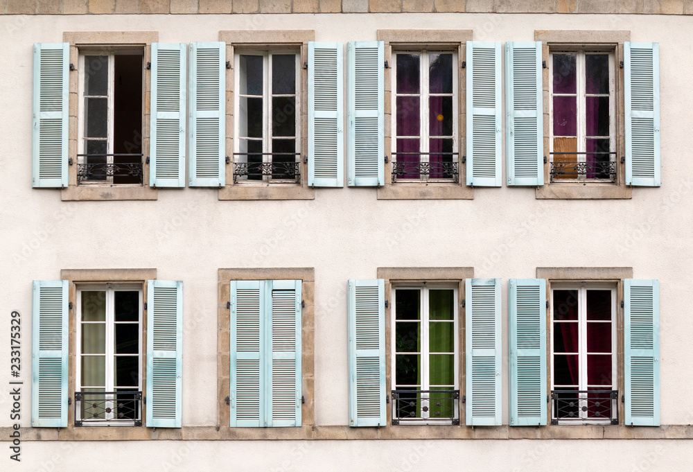 Eight windows with shutters open and closed on a building in France