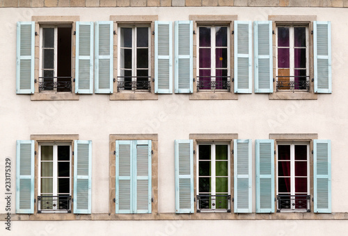 Eight windows with shutters open and closed on a building in France