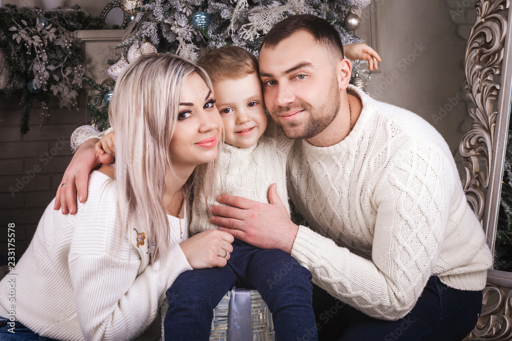 happy lovely family gathered near a Christmas tree and decorations. mother and father hugging a baby boy . concept of the new year holiday happy lovely family gathered near a Christmas tree and decorations. mother and father hugging a baby boy . concept of the new year holiday