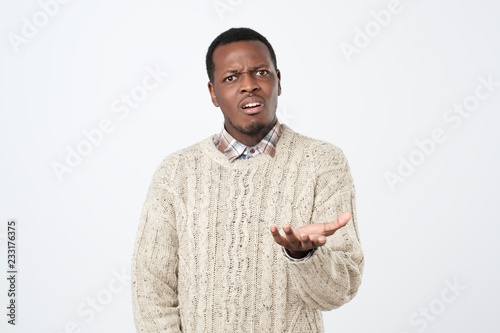 Photography African clueless young man, arm out asking who cares so what.