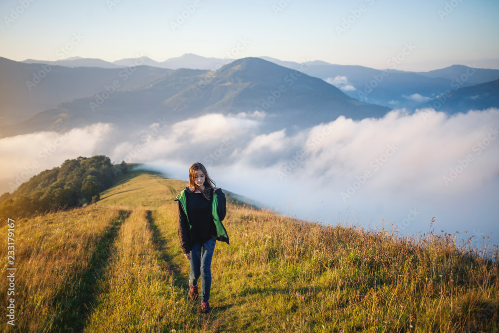 Teenager Girl is Walking through the Mountain Field in the Morning