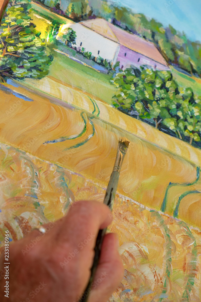 Fototapeta premium Close up of the hand and brush of a lady artist painting a landscape.