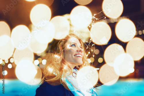 фотографія Happy young woman amazed by LED fairy lights at city outdoor